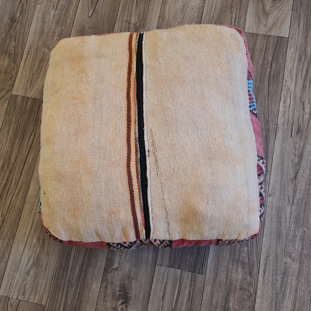 The bottom of the square pouf, showing a simple, light-colored flat-weave fabric with a large black zipper for stuffing
