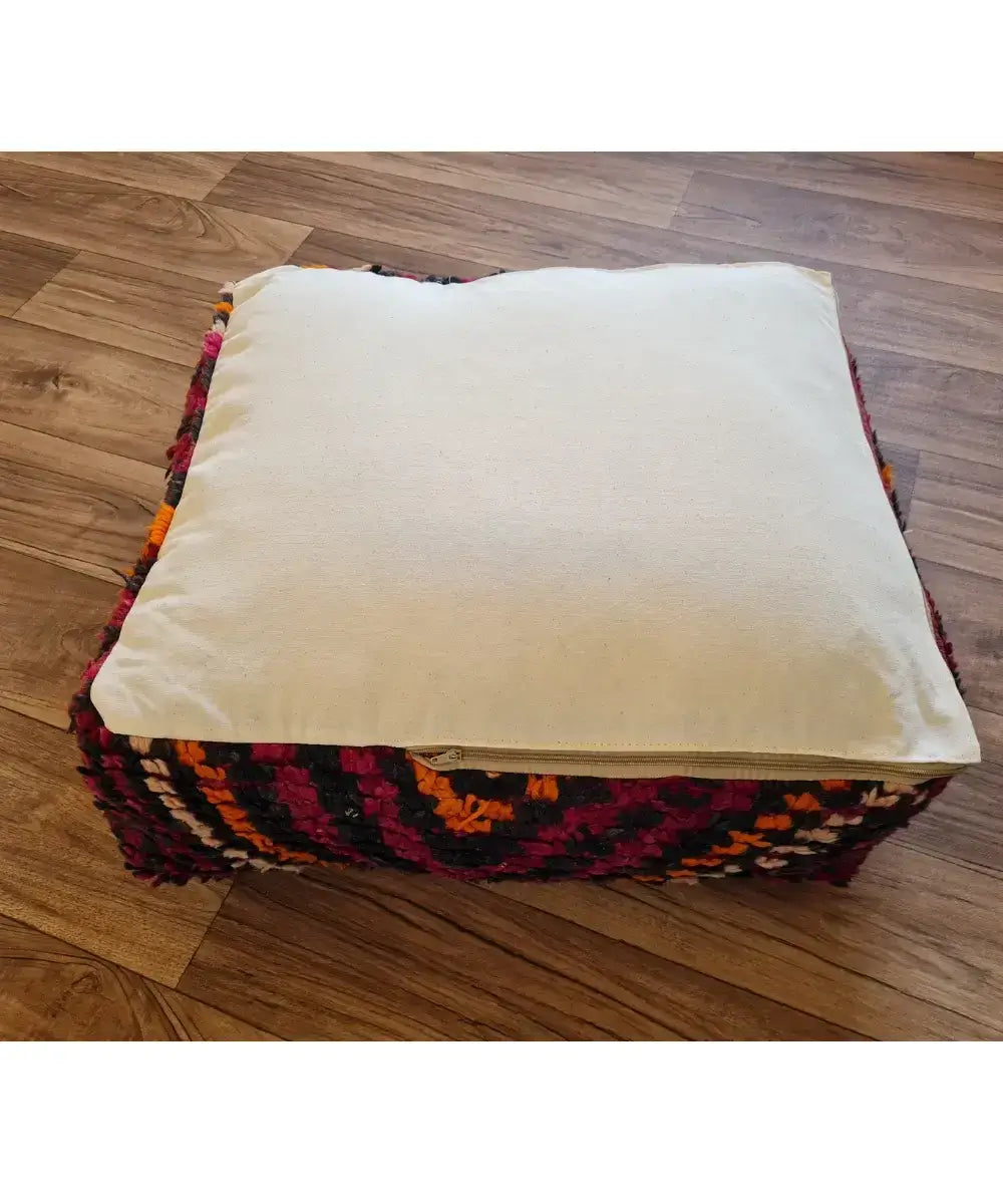 The bottom of the square pouf, showing a simple, off-white cotton canvas back with a large black zipper for stuffing