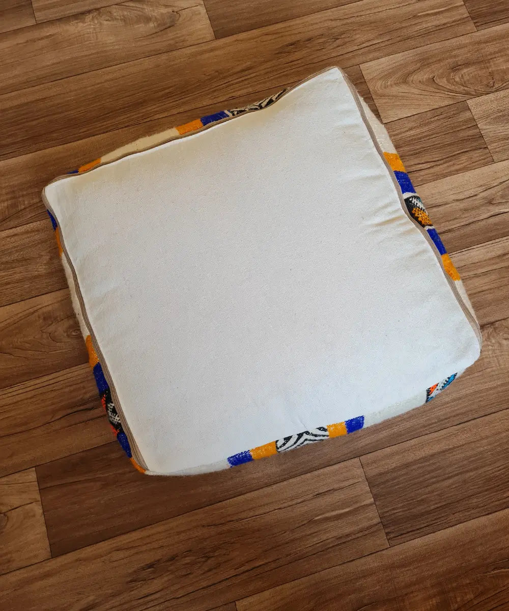 The bottom of the square pouf, showing a simple, off-white cotton canvas back with a large zipper for stuffing