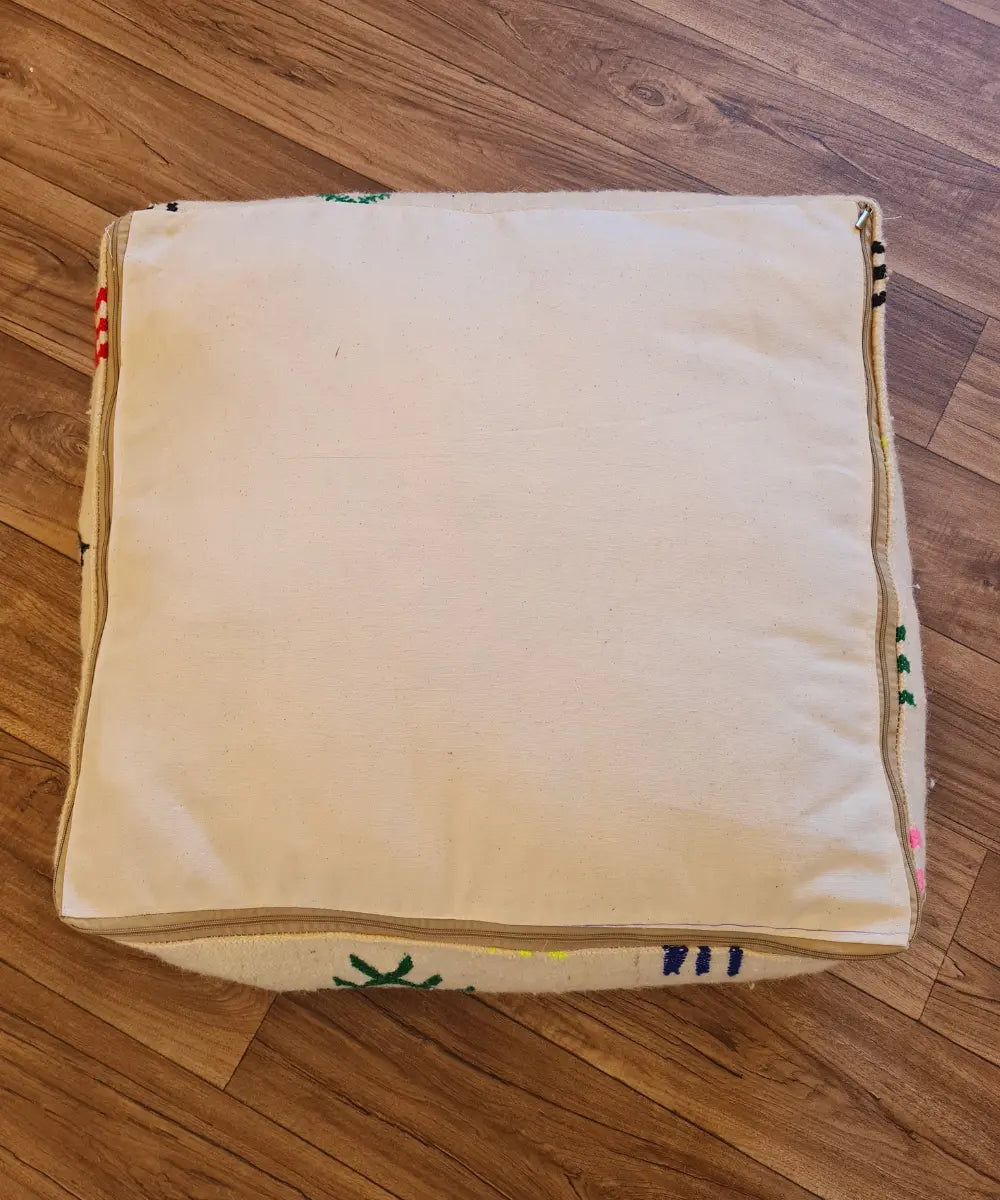 The bottom of the square pouf, showing a simple, off-white cotton canvas back with a large zipper for stuffing