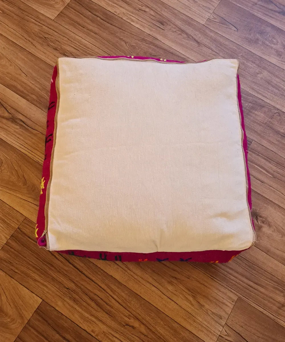 The bottom of the square pouf, showing a simple, off-white cotton canvas back with a large zipper for stuffing
