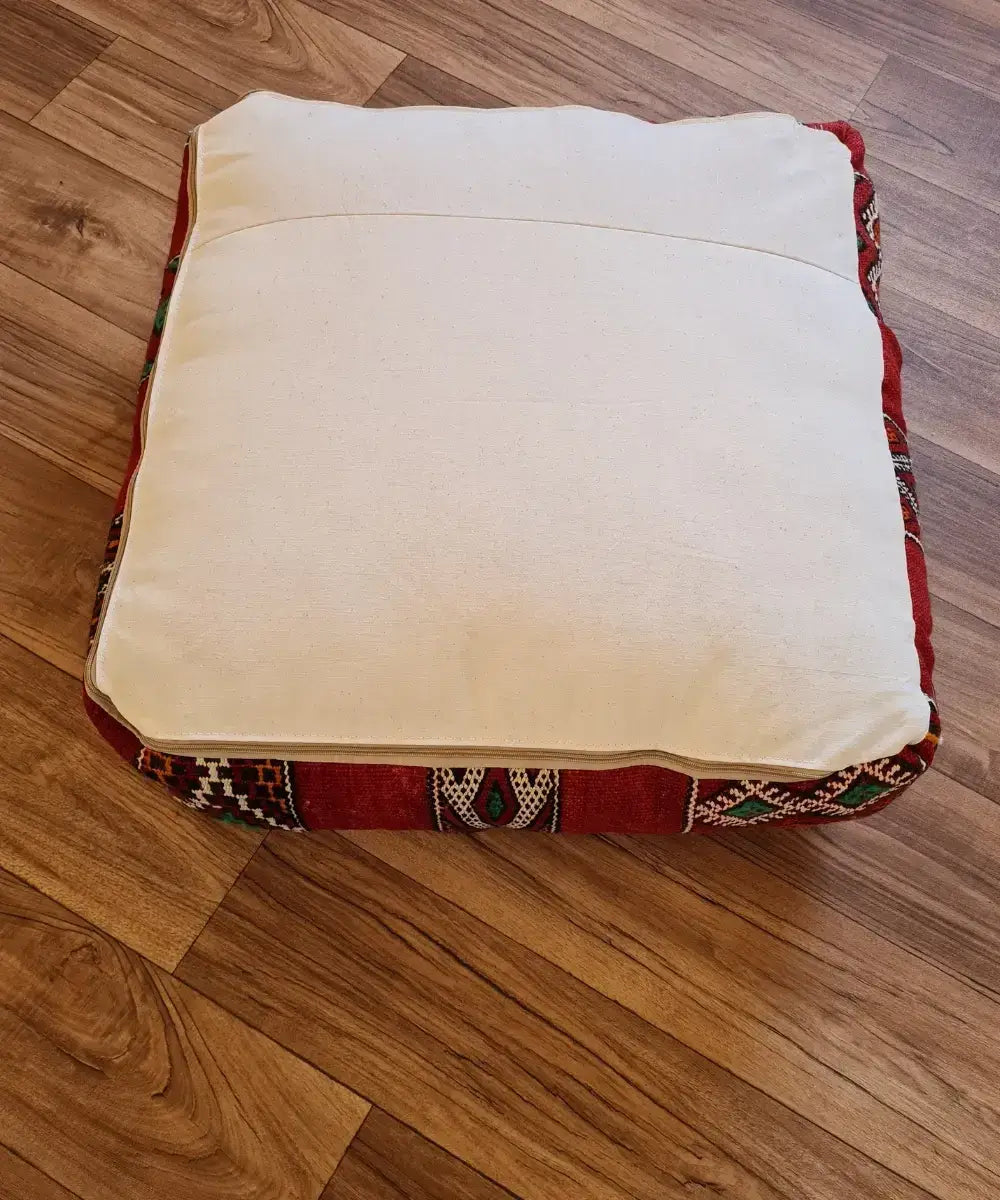 The bottom of the square pouf, showing a simple, off-white cotton canvas back with a large zipper for stuffing