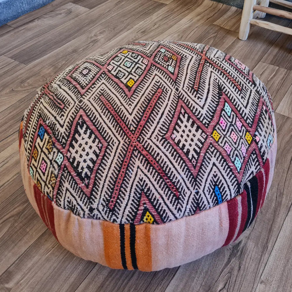 A detailed close-up shot of the intricate woven texture of a vintage Kilim rug, showing the geometric patterns in black, red, and beige with small colorful accents.