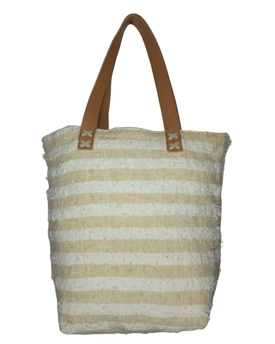 A front-view of a handmade boho-glam tote bag. The bag's body is made of textured cream eyelash fringe and is decorated with a grid of shimmering gold sequins. It features two tan-brown leather shoulder straps, and its dimensions are displayed on the image.
