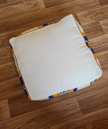 The bottom of the square pouf, showing a simple, off-white cotton canvas back with a large zipper for stuffing