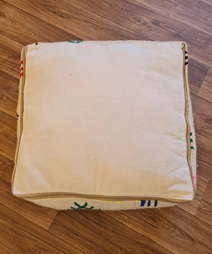 The bottom of the square pouf, showing a simple, off-white cotton canvas back with a large zipper for stuffing