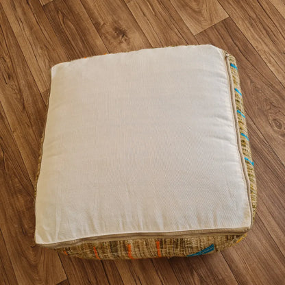 The bottom of the square pouf, showing a simple, off-white cotton canvas back with a large zipper for stuffing
