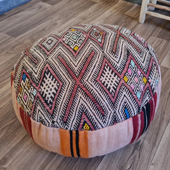 A detailed close-up shot of the intricate woven texture of a vintage Kilim rug, showing the geometric patterns in black, red, and beige with small colorful accents.