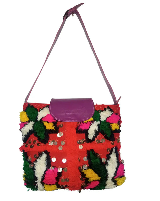 Colorful handbag with a textured surface and pink strap on a white background