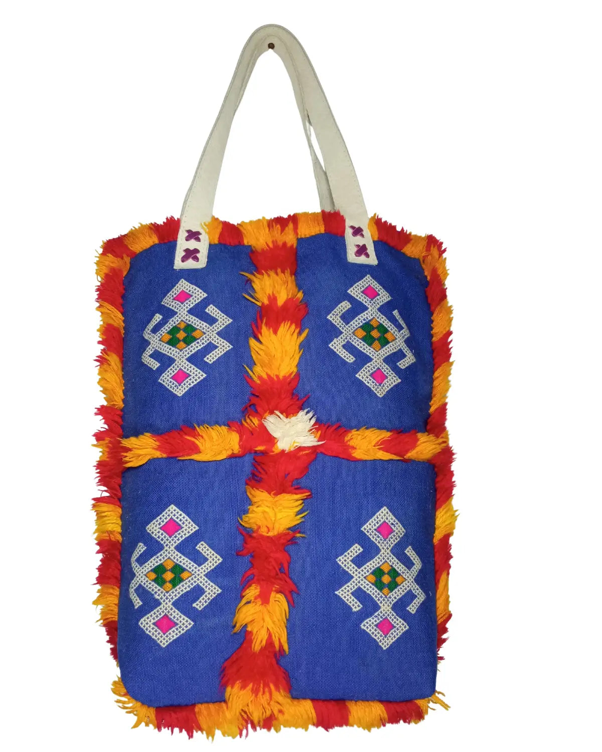 A front-view of a handmade Moroccan Berber-style tote bag on a white background. The bag is made of royal blue fabric with four panels of geometric embroidery and is trimmed with shaggy red and yellow wool fringe. It has off-white shoulder straps, and its dimensions are displayed.