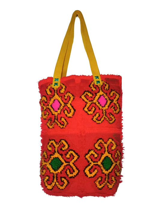 Red bag with colorful embroidery and yellow handles on a white background