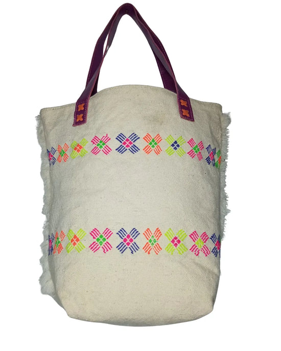 Detailed view of the vibrant neon embroidery on the white faux fur material of a retro tote bag, showing the star-shaped patterns in fuchsia, lime green, and orange.