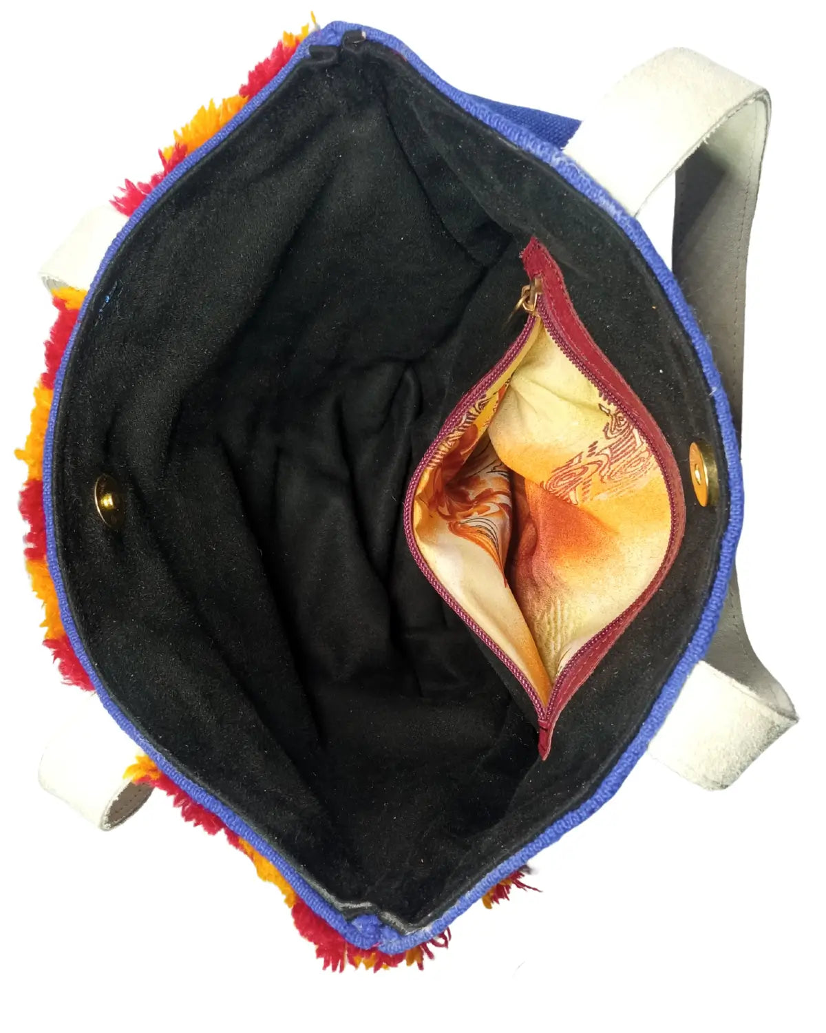A front-view of a handmade Moroccan Berber-style tote bag on a white background. The bag is made of royal blue fabric with four panels of geometric embroidery and is trimmed with shaggy red and yellow wool fringe. It has off-white shoulder straps, and its dimensions are displayed.