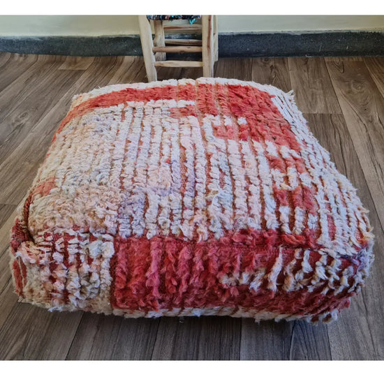 The side profile of a square vintage rug pouf, showing the thick, plush wool texture and mixed colors of the high-pile rug material