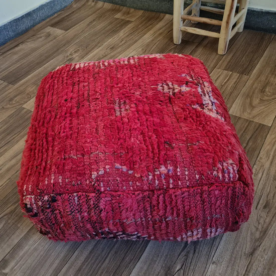 The side profile of a square vintage rug pouf, showing the thick, plush wool texture and colorful patterns