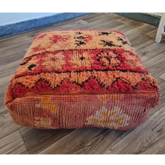 The side profile of a square vintage rug pouf, showing the thick, plush wool texture and colorful patterns