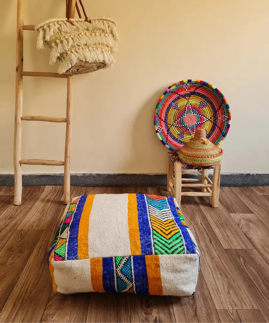 The side profile of a square modern Kilim pouf, showing the durable woven texture and the continuation of the colorful geometric and striped patterns
