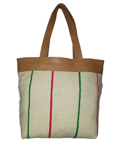 The reverse side of the tote bag, showing a cream woven fabric with vertical red and green stripes and tan leather handles
