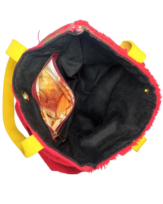 Red bag with yellow handles and black interior, containing a transparent bag with orange contents.