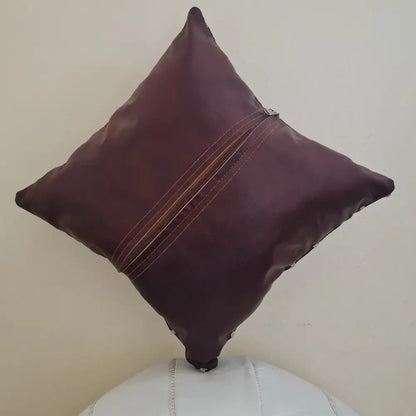 The back of a square brown leather pillow cover, showing the long zipper used for inserting a pillow form